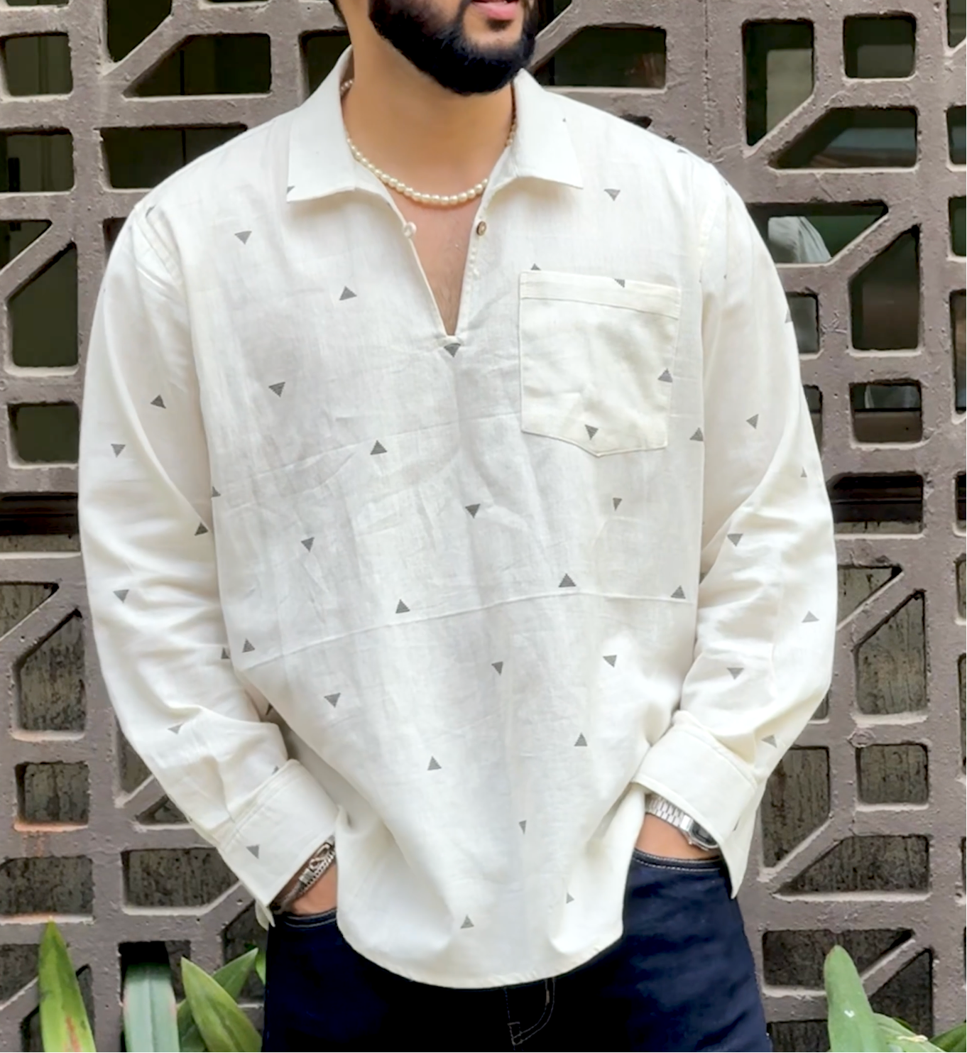 Person wearing a white shirt with black patterns in an outdoor setting.